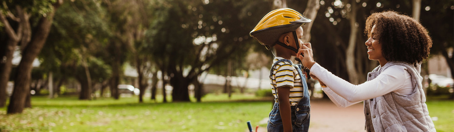 Woman putting on son's bike helmet.