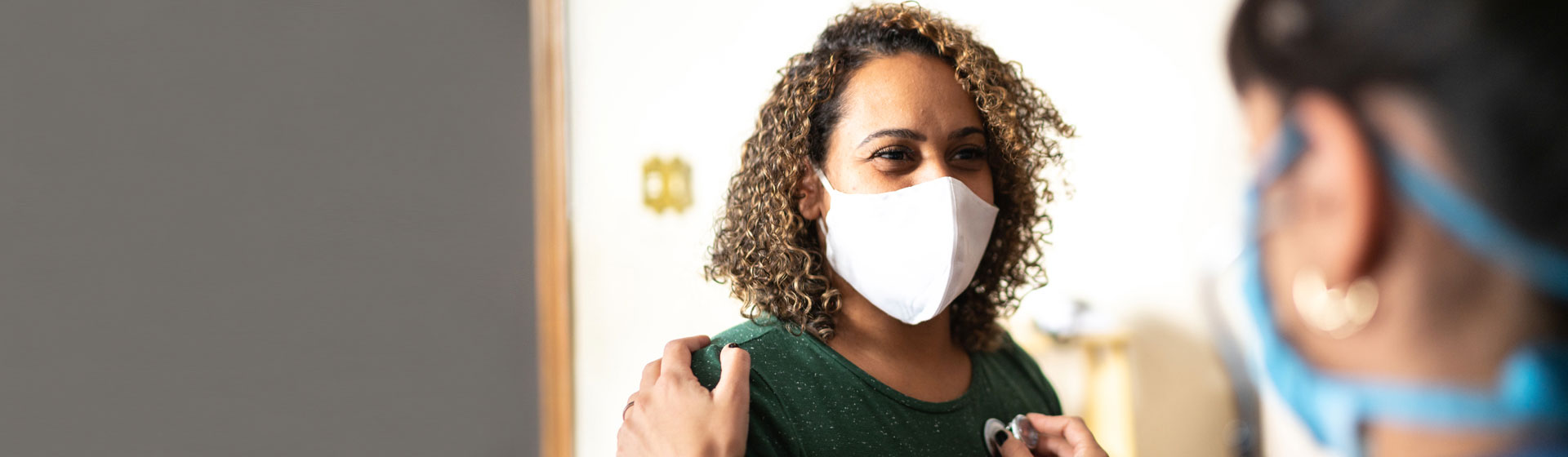 Masked female patient speaking with female doctor